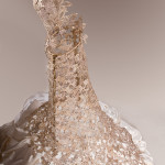 Cast lace white bronze metal wedding dress on a cream background with sateen under.