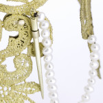 Metal lace collar front view of needle clasp with pearl chain on a white background.